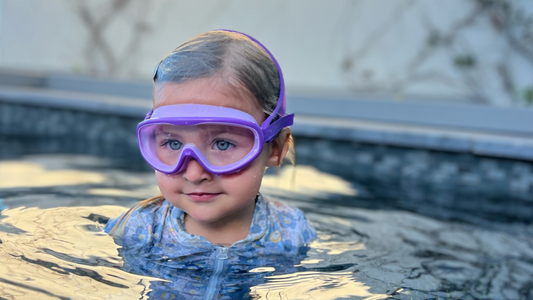 Blonde girl wearing Frogglez purple half mask swimming goggles. Frogglez goggles are the most comfortable swim goggles for kids. Swimming goggles protect kids eyes from sunlight and chlorine.