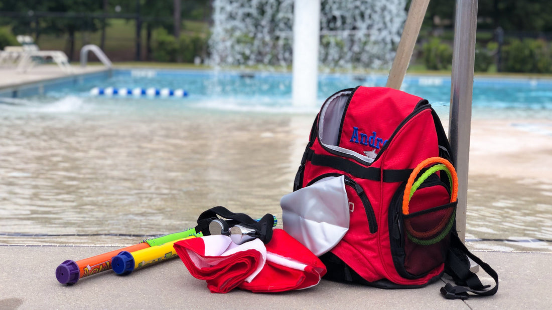 Frogglez swim goggles and swimming toys on red swim bag by swimming pool