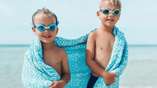 Boy wearing green Frogglez swim goggles while floating in a swimming pool at swim lessons